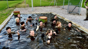 A group of colleagues on a leadership course plunge into cold water.